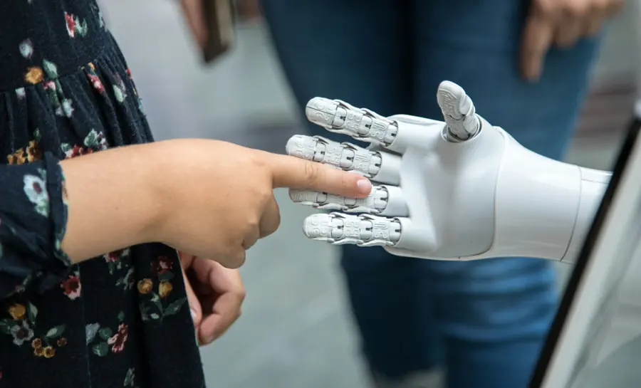 A child's finger touching the fingertip of a white robotic hand